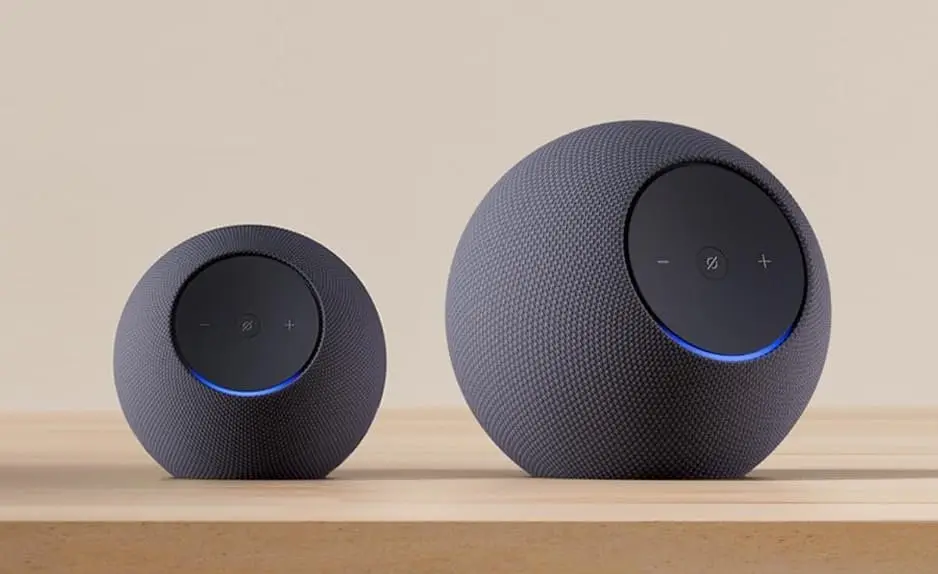 El Echo Dot Max a la izquierda y el Echo Studio a la derecha sobre una repisa de madera: el Studio es visiblemente más grande, casi el doble de alto